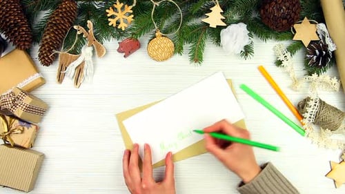 Writing Christmas Card with Christmas Decorations on Table