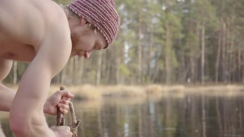 Shirtless Man Holding Branch Near Lake in Forest