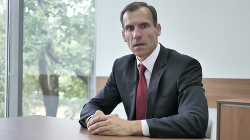 Shocked Man Reacting to Bad News at Desk