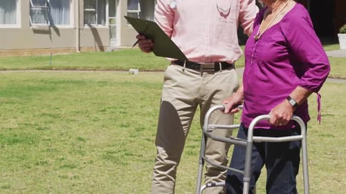 Doctor walking with a senior woman in the park of a retirement home