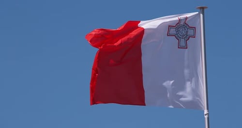 The Flag of Malta Waves Against Blue Sky