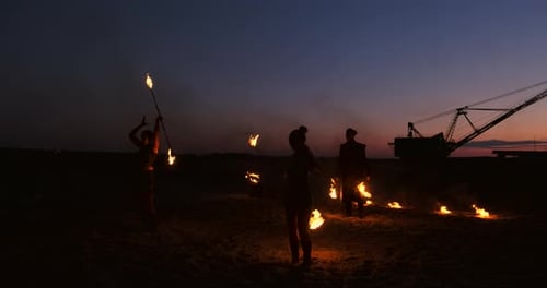 Feuershow Drei Frauen in ihren Händen drehen brennende Speere und Fächer im Sand mit einem Mann mit zwei