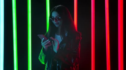 Stylish Woman Using Phone with Neon Lights Background