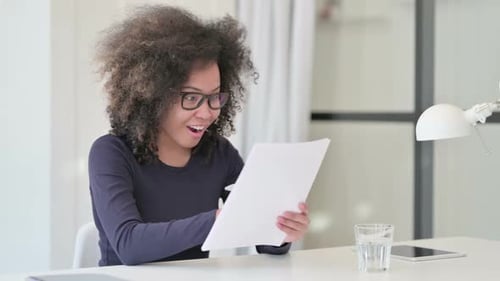 Woman Smiling and Writing on Paper at Desk