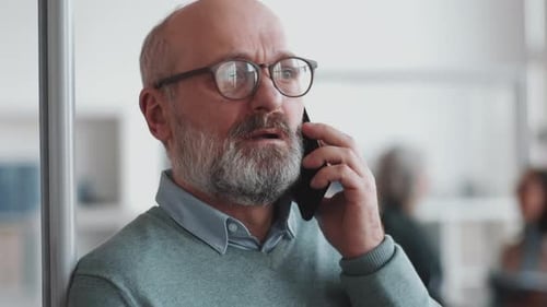 Elderly Businessman Speaking on Mobile Phone in Office