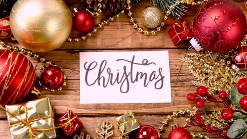 Eine Karte mit dem Text WEIHNACHTEN mit Dekorationen auf einem Holztisch vergrößern
