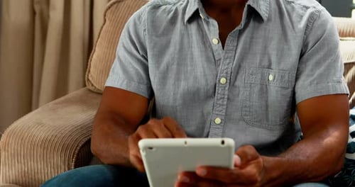 Handsome man using digital table in living room 4k