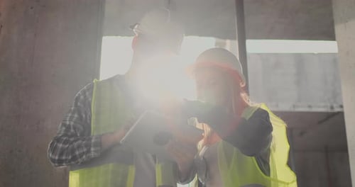 Bauarbeiter Mann und Architektin in einem Helm besprechen den Plan des Baus des Hauses