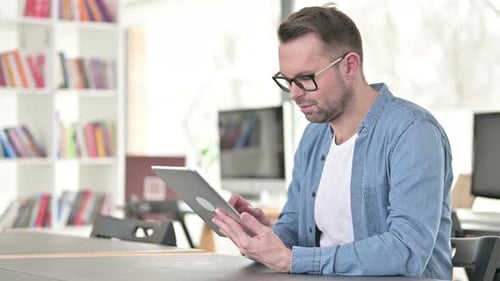 Man Using Tablet at Table in Office Setting