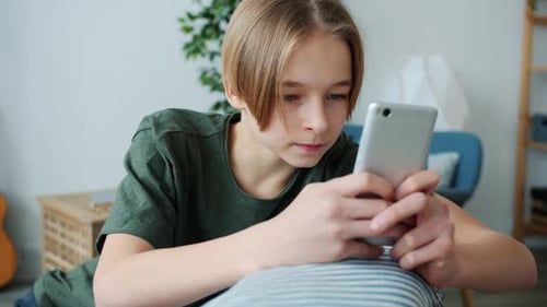 Teenager Using Smartphone, Lying Indoors
