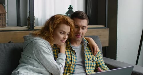 Couple Using Laptop Computer Together at Home on Couch