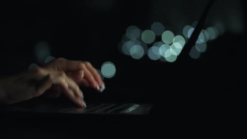 Female Hands is Typing on a Laptop at Night