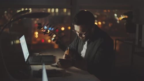 Young Businessman Working in Dark Office at Night