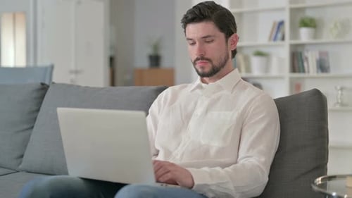 Man Works on Laptop While Sitting on Couch