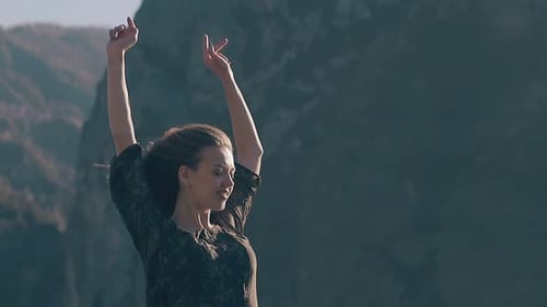 Woman Standing With Arms Raised In Mountainous Landscape