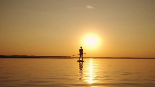 Paddleboarding Silhouette at Sunset on Calm Waters