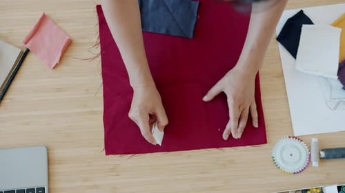 Fashion Designer Tracing Pattern on Burgundy Fabric