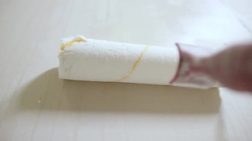 Paint Roller Applying White Paint to Surface