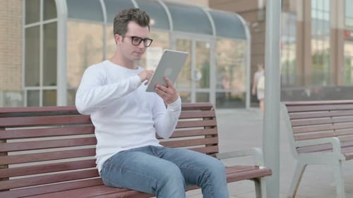 Young Adult Using Tablet on a Park Bench