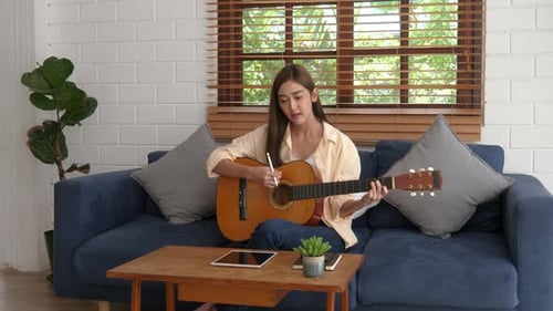 Young Woman Plays Guitar at Home