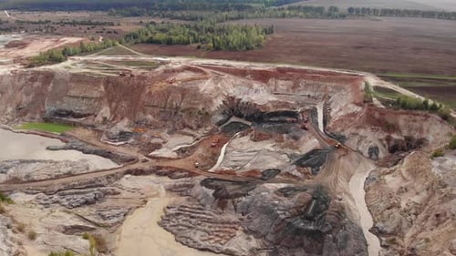 Cantera minera industrial a cielo abierto con muchas excavadoras y camiones en funcionamiento.