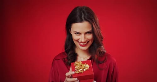 Woman Holding Present Smiling on Red Background