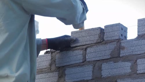 Close Shot at the Bricklayer's Hands, Male Volunteer Worker Lays Brick Into Wall with Cement Using