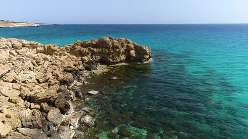 Aerial Top View Footage By Drone of Ocean Blue Water and Rocks A Calm Sea Washes the Rocky Mountain