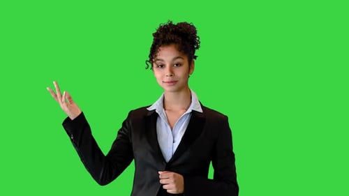African AMerican Businesswoman Talking on Camera and Pointing at a Blank Space on a Green Screen