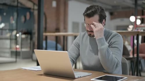 Tired Man Working at Laptop in Office