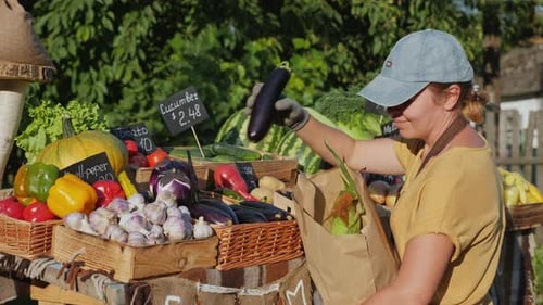 Woman at the Farmers Market Puts a Set of Vegetables in a Paper Bag