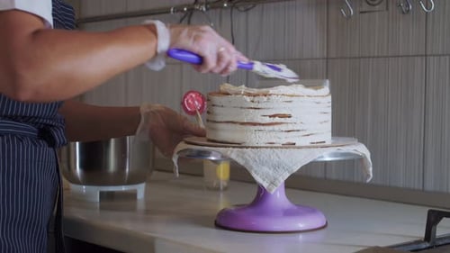 Woman Decorates Layered Cake with White Icing