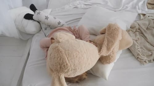 Happy Girl Receives Stuffed Animal on Bed