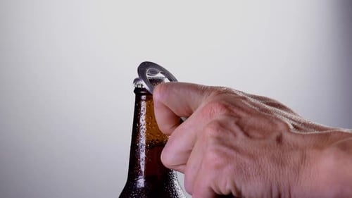 Hand Opens Cold Beer Bottle with Opener