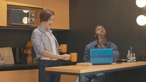 Woman Brings Coffee to Man Working on Laptop