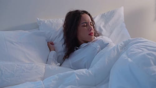 Latino beautiful woman lying down on bed in bedroom in dark night room.