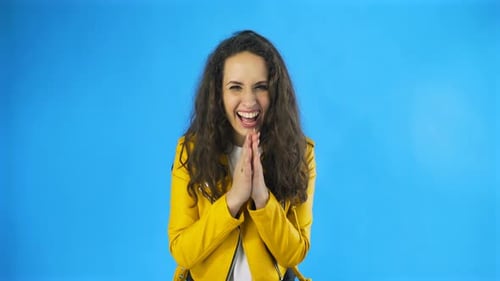 Young Joyful Woman Having Fun Laughing Covering Her Mouth with Hands in Studio with Blue Background.