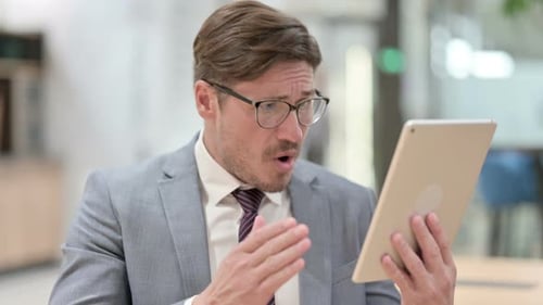 Shocked Businessman Using Tablet in Office Setting