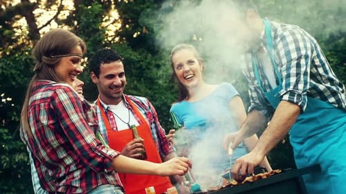 Friends Grilling and Drinking at an Outdoor Barbecue