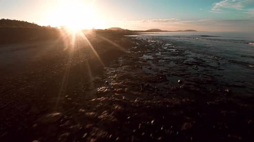 Aerial view flying along tranquil coast at sunset