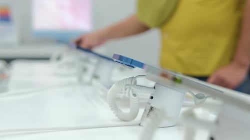 An Unrecognizable Man in an Electronics Store Chooses a New Smartphone for Himself