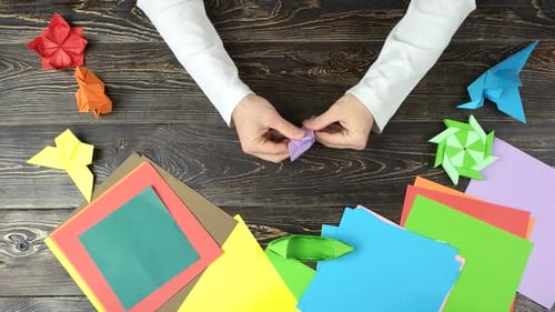 Männerhände machen Origami-Blume.