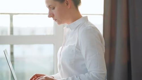 Frau sitzt auf der Couch und arbeitet an einem Laptop. Konzept der Remote-Arbeit