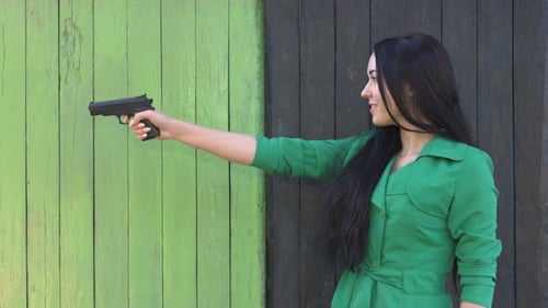 Woman Holding Handgun, Outdoors in Daytime