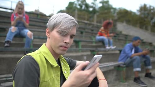 Teens Using Mobile Phones on Stadium Bleachers