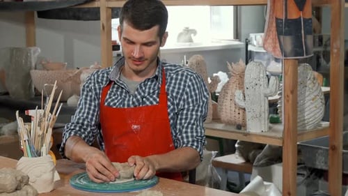 Junger männlicher Keramikkünstler lächelt bei der Arbeit in die Kamera