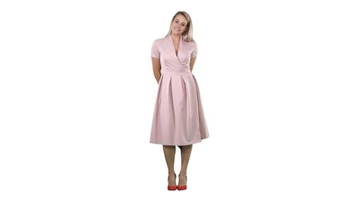 Happy beautiful woman in pink dress posing on white background.