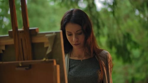 Woman Painting Outdoors in a Green Forest
