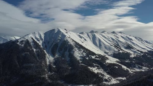 Air Flight Through Mountain Clouds Over Beautiful Snowcapped Peaks of Mountains and Glaciers