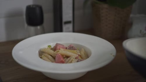 Pasta Being Plated with Meat and Cream Sauce